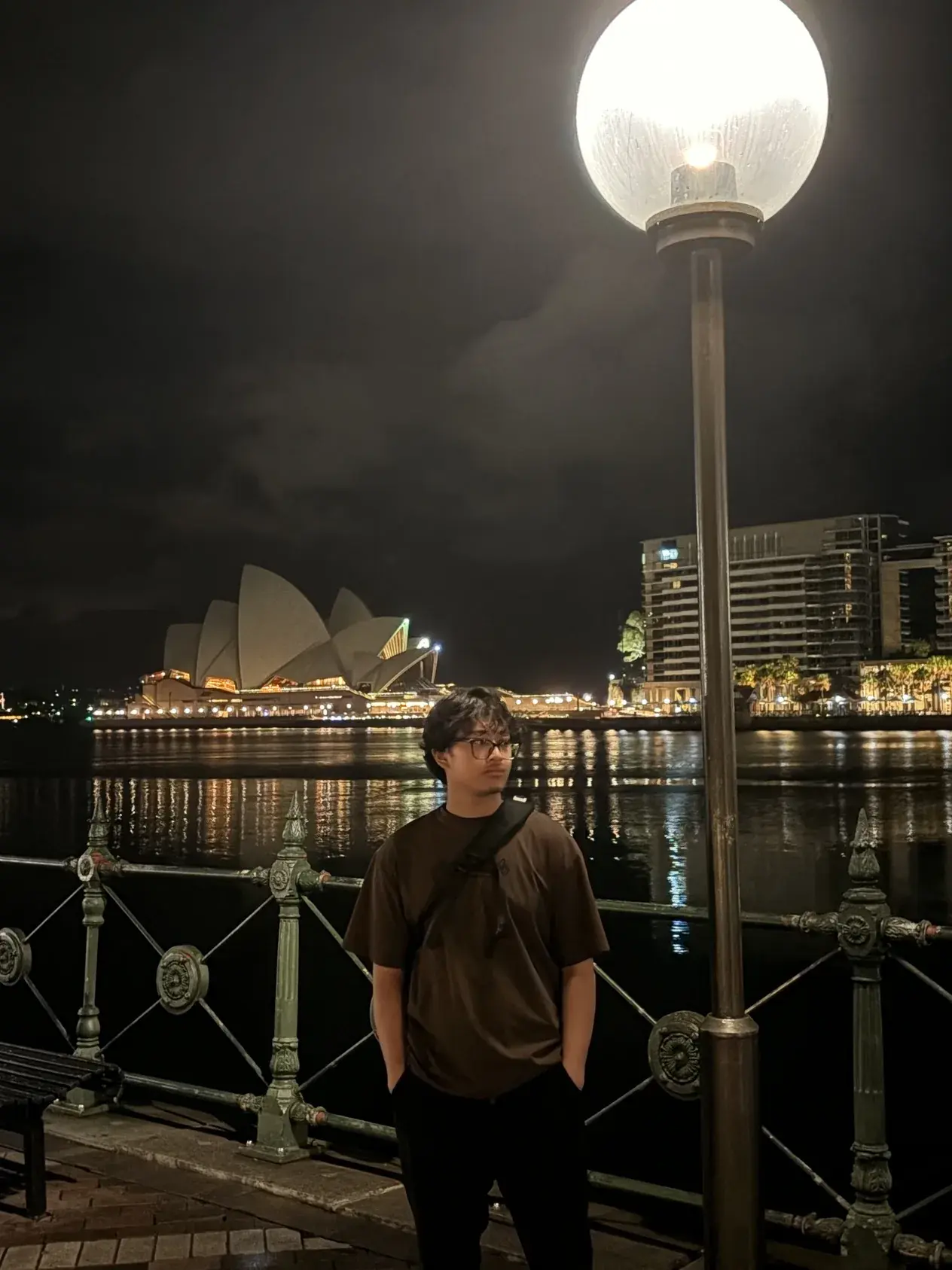Aatish standing on the Sydney harbour foreshore at night, the lit Opera House behind him.